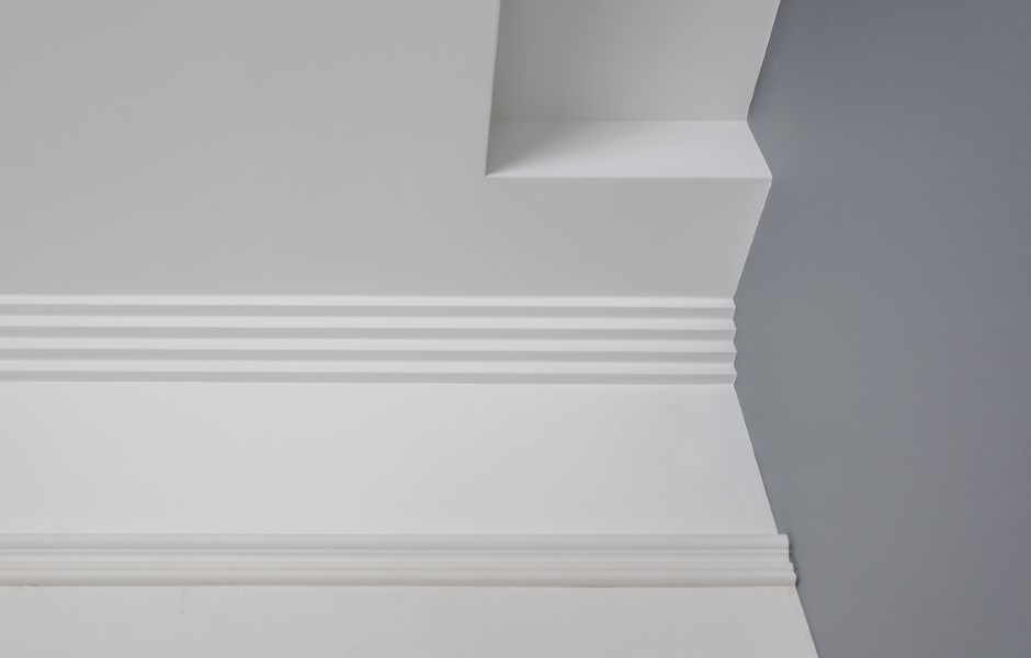 Image of a corner of a ceiling with white art deco crown molding.