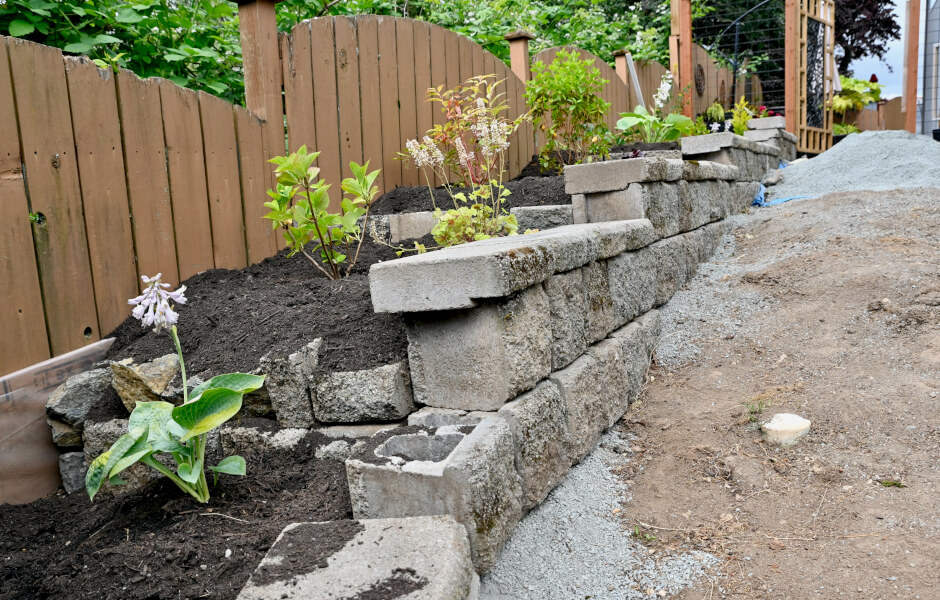 Image of a sloped patio with rock terracing, featuring brick and stone walls used for flower and vegetable beds.