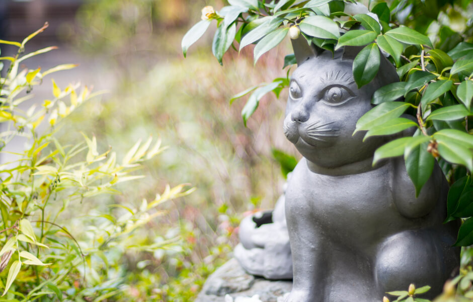 Image of a rock statue of a cat in a garden.