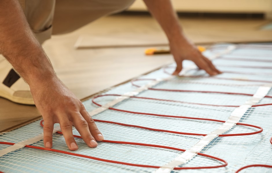 Image of a professional worker is shown installing an electric radiant underfloor heating system indoors